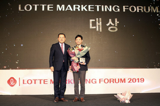 롯데는 28일 서울 잠실 롯데호텔월드 3층 크리스탈볼룸에서 '2019 롯데 마케팅 포럼' 행사를 진행했다. 롯데지주 황각규 부회장이 올 한해 가장 뛰어난 마케팅 성과를 낸 계열사를 선정하는 '마케팅 어워드'에서 대상을 수상한 롯데홈쇼핑 마케팅전략팀 이태호 팀장과 기념촬영을 하고 있다. <롯데 제공>